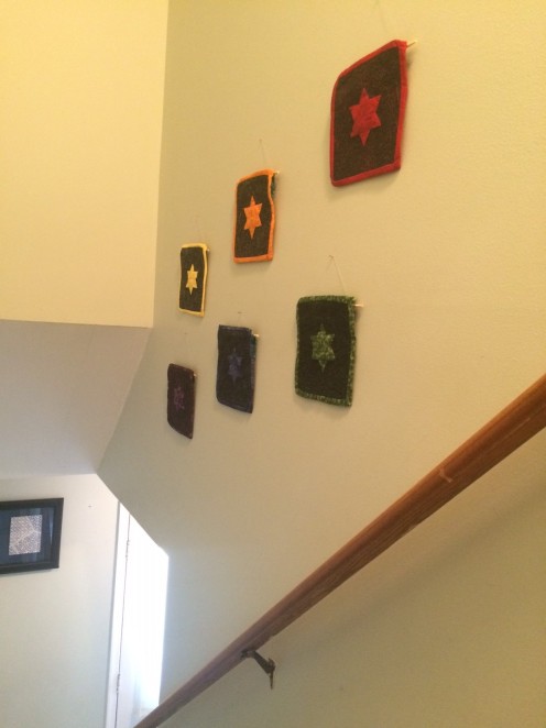 6 quilts hung on a wall, staircase railing visable