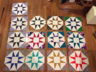 13 12-inch quilt blocks arranged on a wood floor