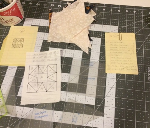 handwritten notes by my grandmother and hand cut templates for the pattern, spread out over a cutting mat.