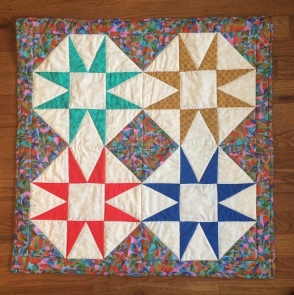 4 quilt squares with matching border fabric and different color interior stars; vintage/1970s style prints.